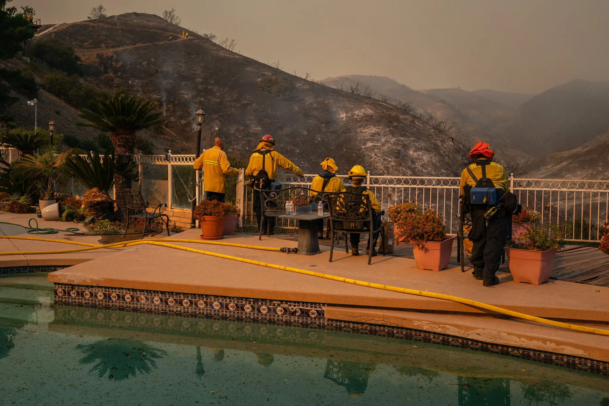 In Mandeville Canyon, firefighters rested with boxes of Gatorade and potato chips as aircrafts circled overhead, 